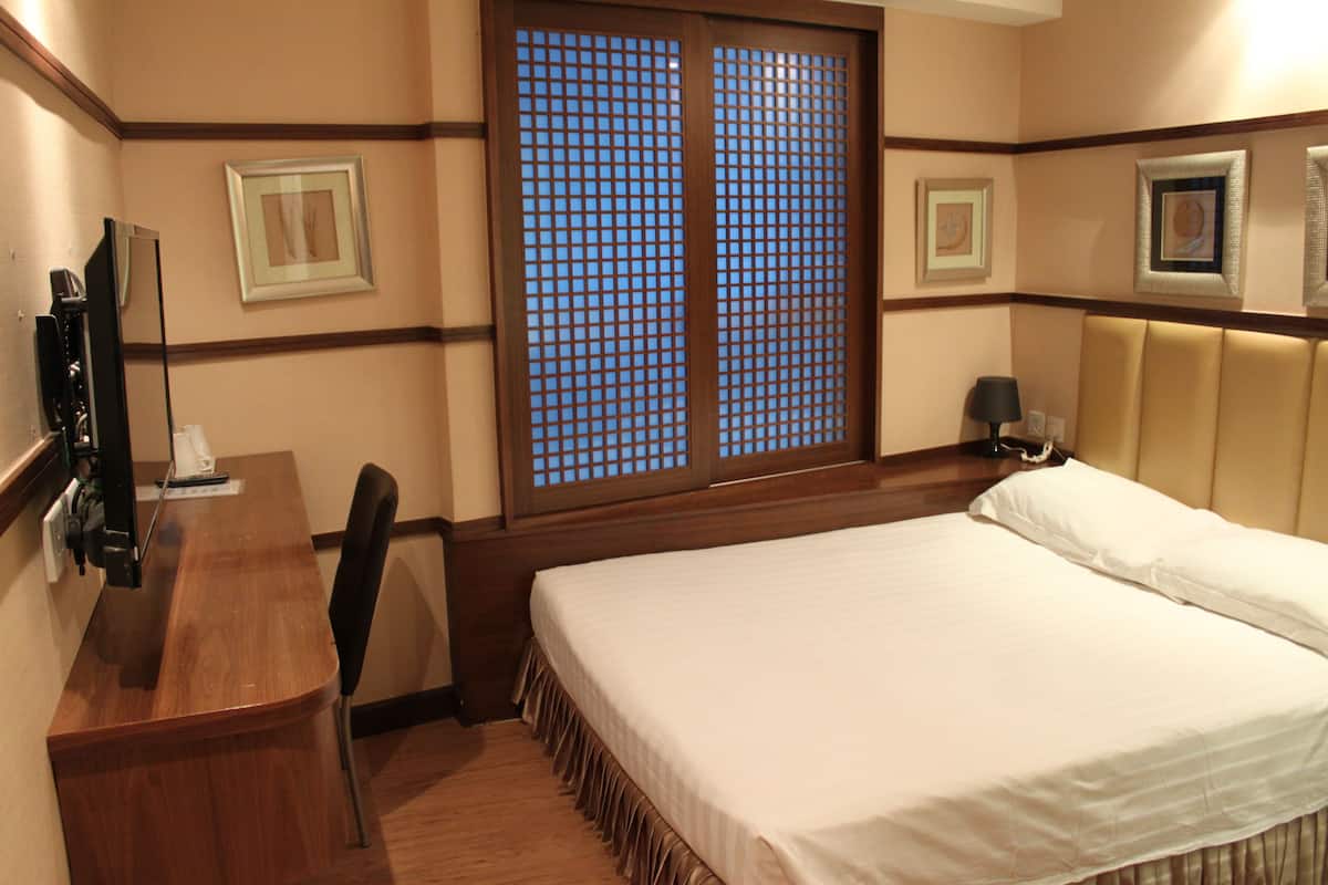 A hotel room with a bed, a desk, a chair, a TV, and a window with a view.
