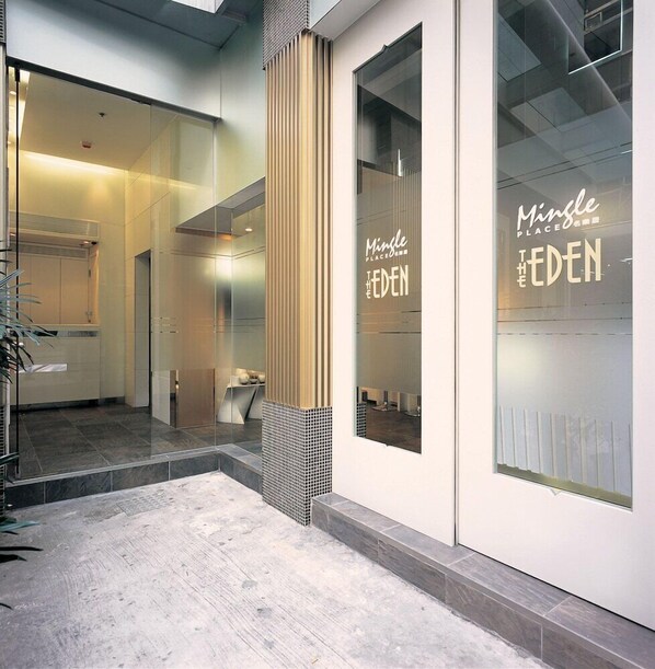 A modern interior with a glass door entrance, a visible restroom, and a tiled floor. - Mingle Place At The Eden (Hong Kong)