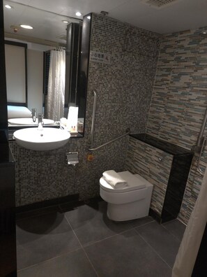 A bathroom with a white sink, mirror, and toilet. The walls are tiled with a mosaic pattern. - Mingle Place At The Eden (Hong Kong)