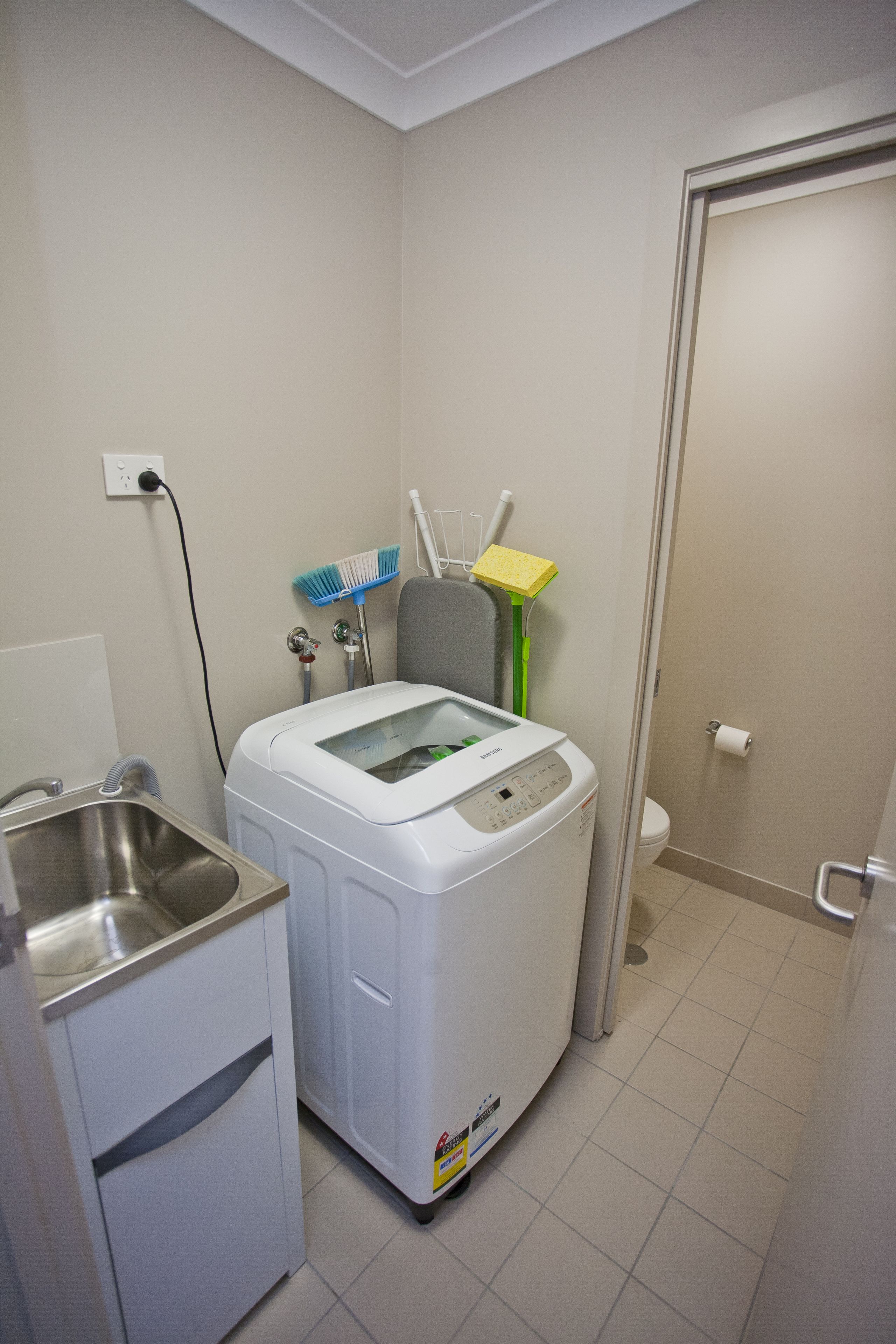 Ein kleiner Hauswirtschaftsraum mit Waschmaschine, Spüle und Toilette.