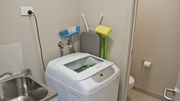 Ein kleiner Hauswirtschaftsraum mit Waschmaschine, Spüle und Toilette.