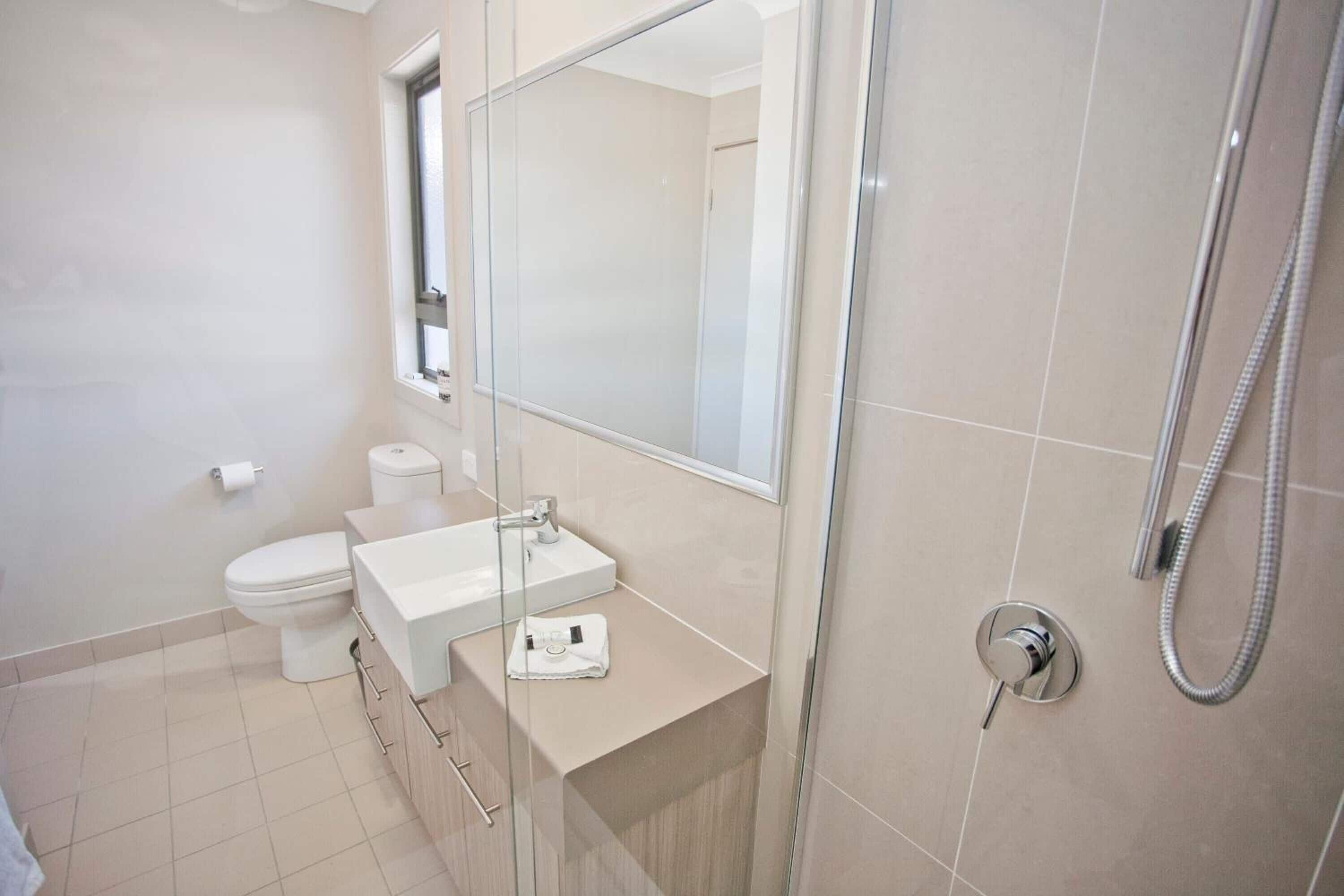 A modern bathroom with a toilet, sink, and shower.