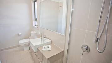 A modern bathroom with a toilet, sink, and shower.