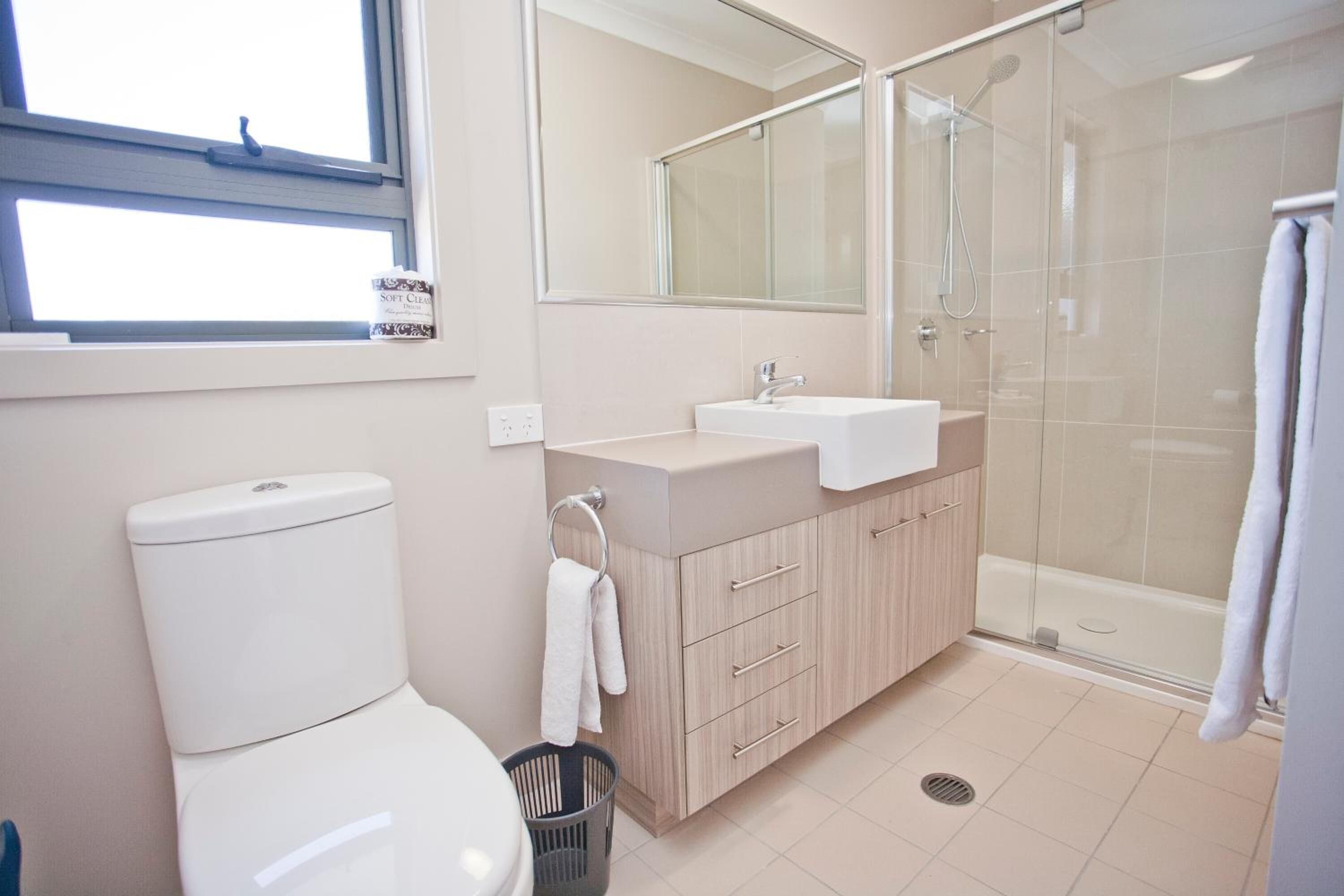 Une salle de bain moderne équipée de toilettes, d’un lavabo et d’une douche.