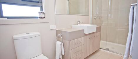 A modern bathroom with a toilet, sink, and shower.