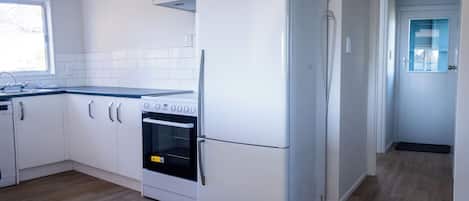 Una cocina moderna con armarios blancos, horno integrado y refrigerador.