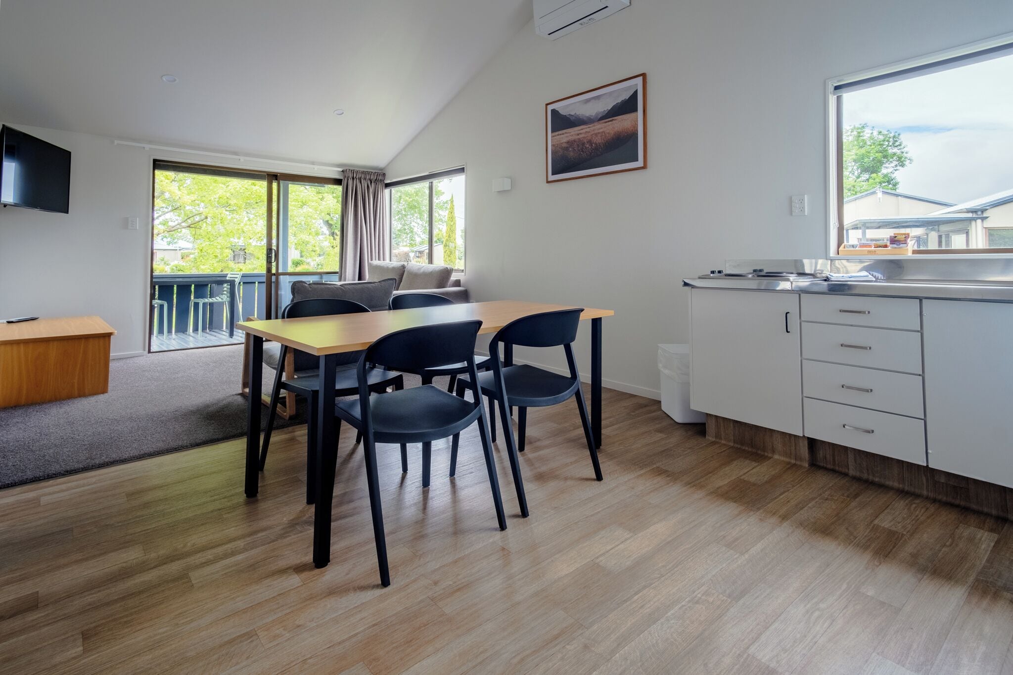 A modern kitchen with a dining area, large windows, and a view of the outdoors.