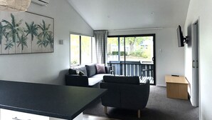 Un salon moderne avec un canapé, une table basse et une vue sur l’extérieur grâce à une grande fenêtre.