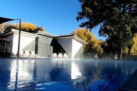 Una piscina al aire libre, sombrillas, sillones reclinables de piscina