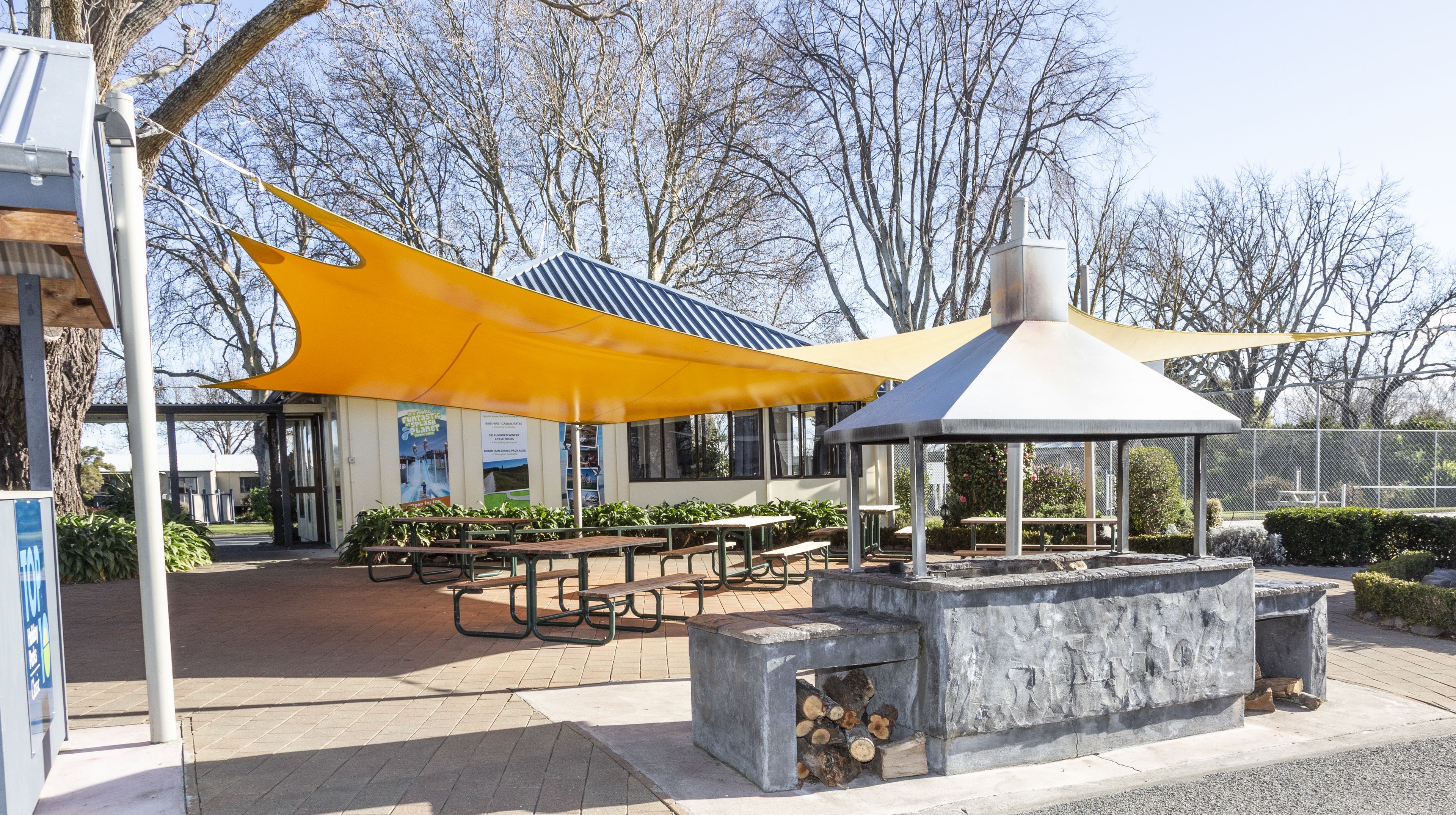 Un parc équipé de tables de pique-nique, d’un kiosque et d’un bâtiment où sont exposées des affiches à caractère éducatif.