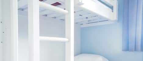 Una cama litera con ropa blanca y suelo de madera.