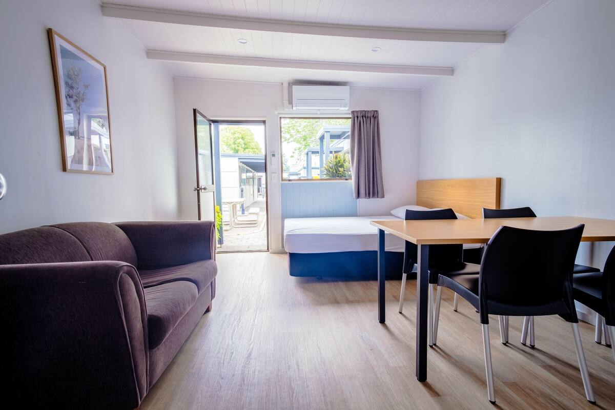 Een moderne kamer met een bed, een eettafel en een bank.