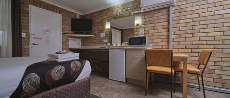 Ein Hotelzimmer mit einem Bett, einem Schreibtisch, einem Sessel, einem Fernseher und einer Mikrowelle.