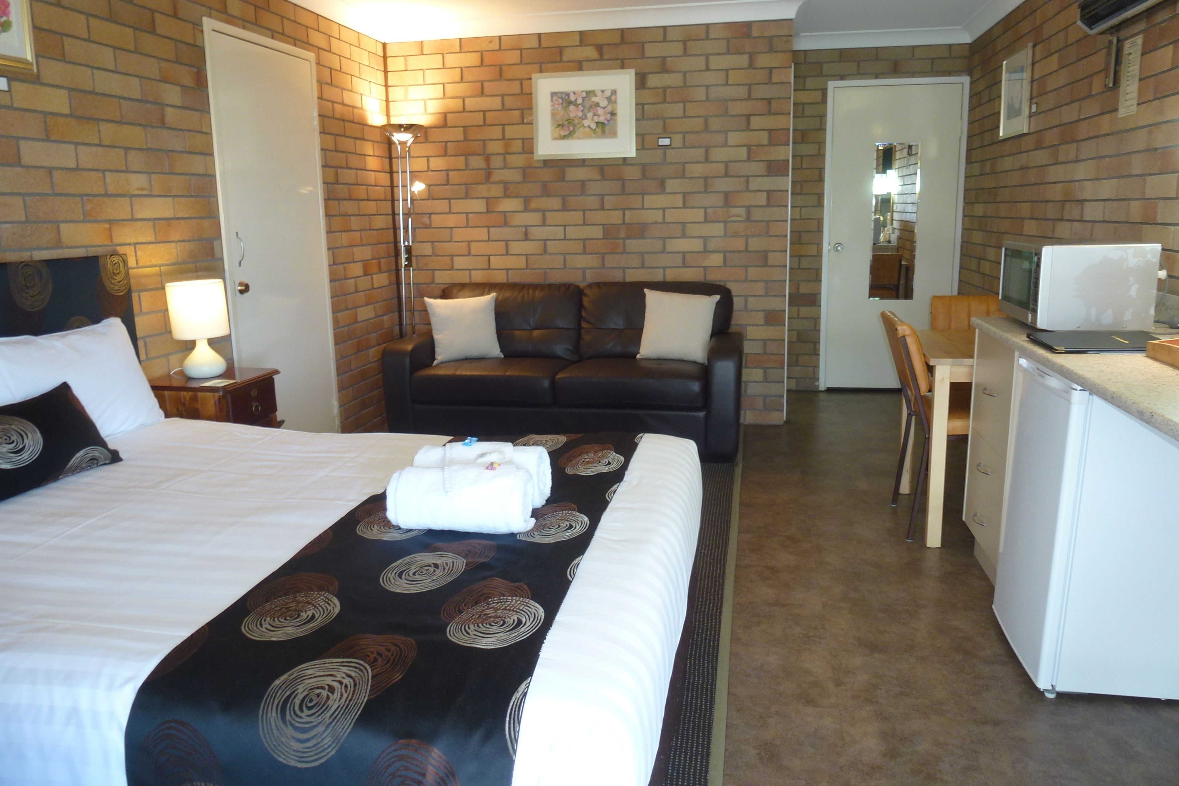 A hotel room with a bed, a sofa, a desk, and a television.