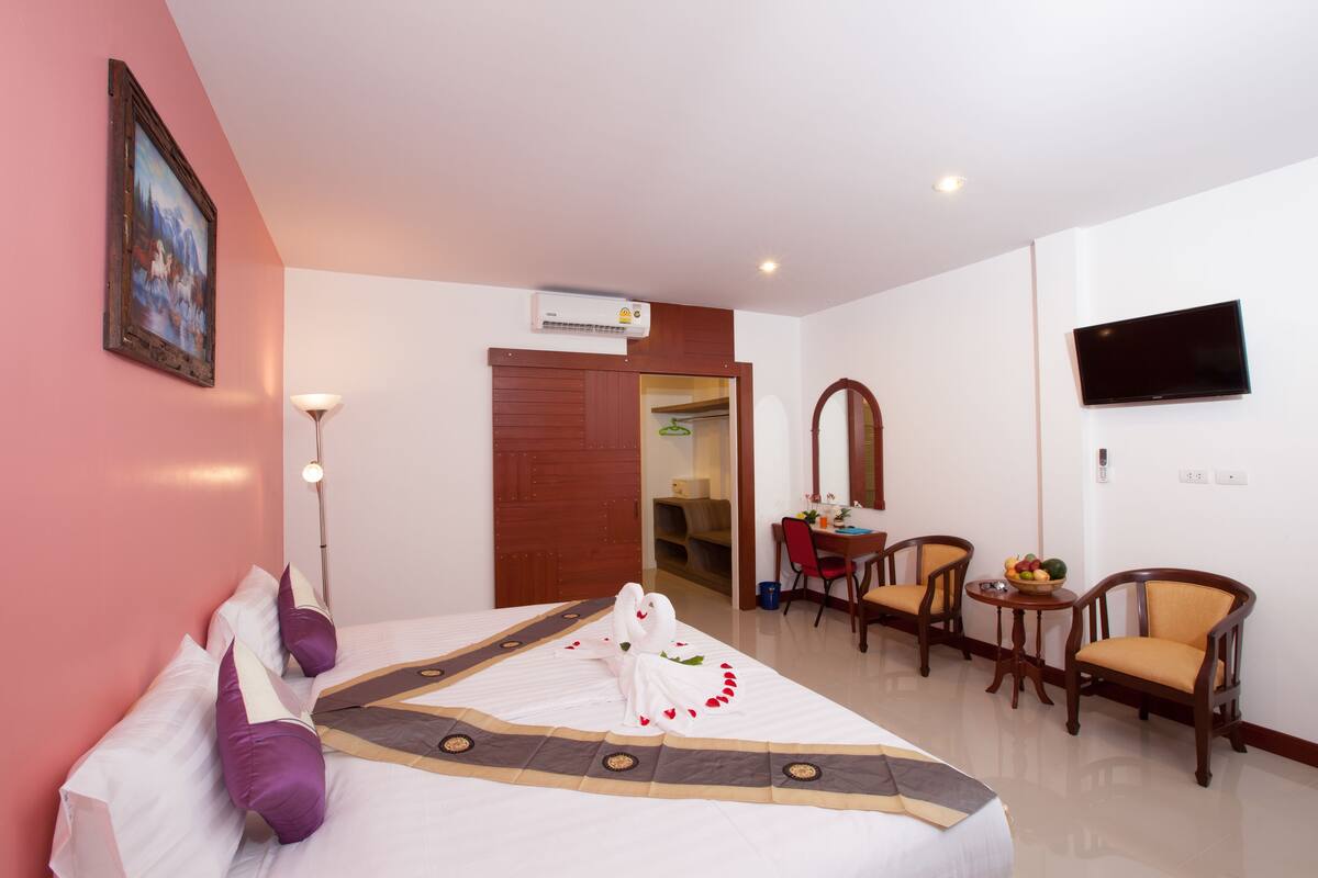 Une chambre d’hôtel avec un lit, un bureau avec des chaises, une télévision et un tableau au mur.