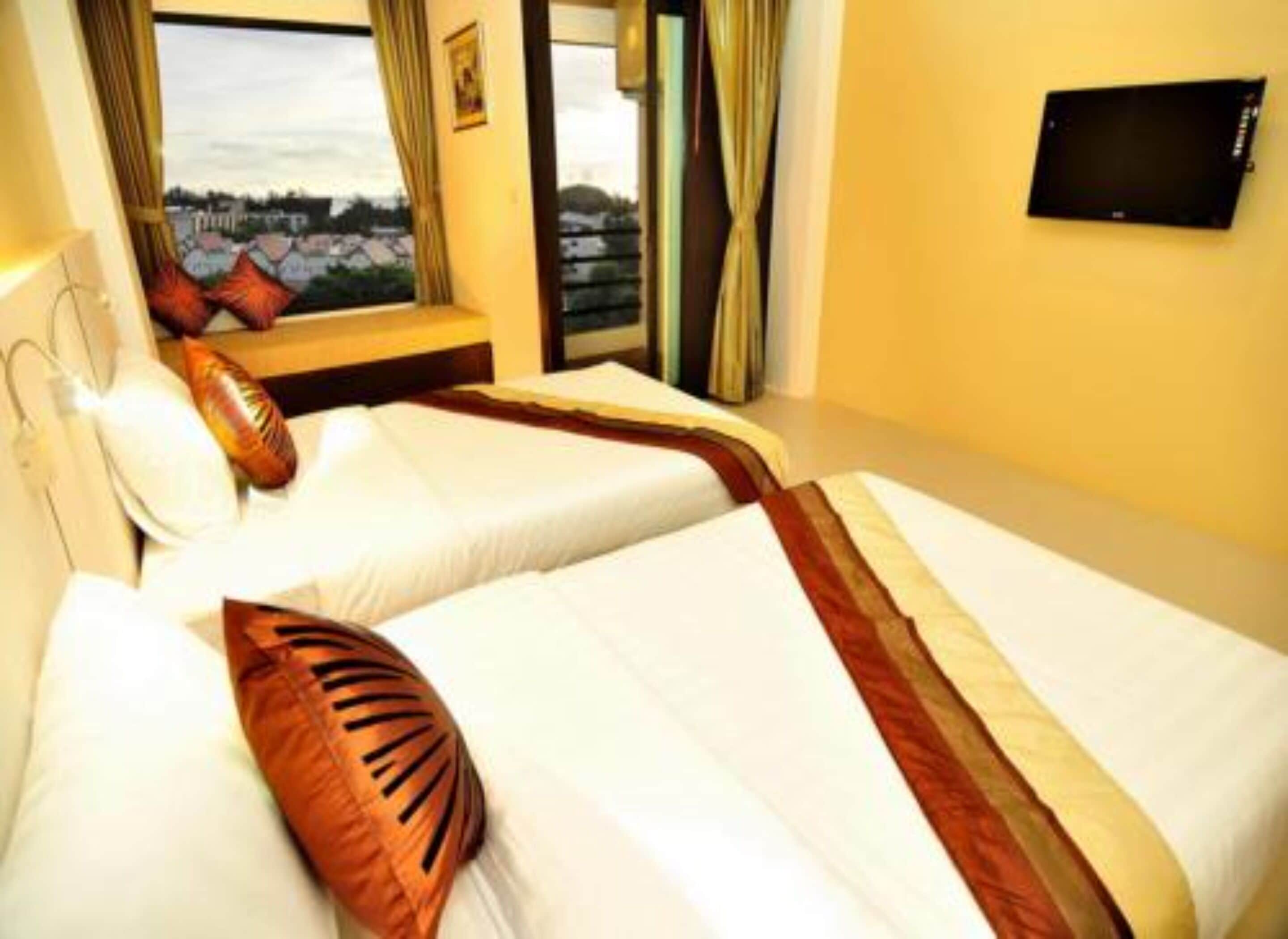 A hotel room with two beds, a flat-screen TV mounted on the wall, and a window with curtains.