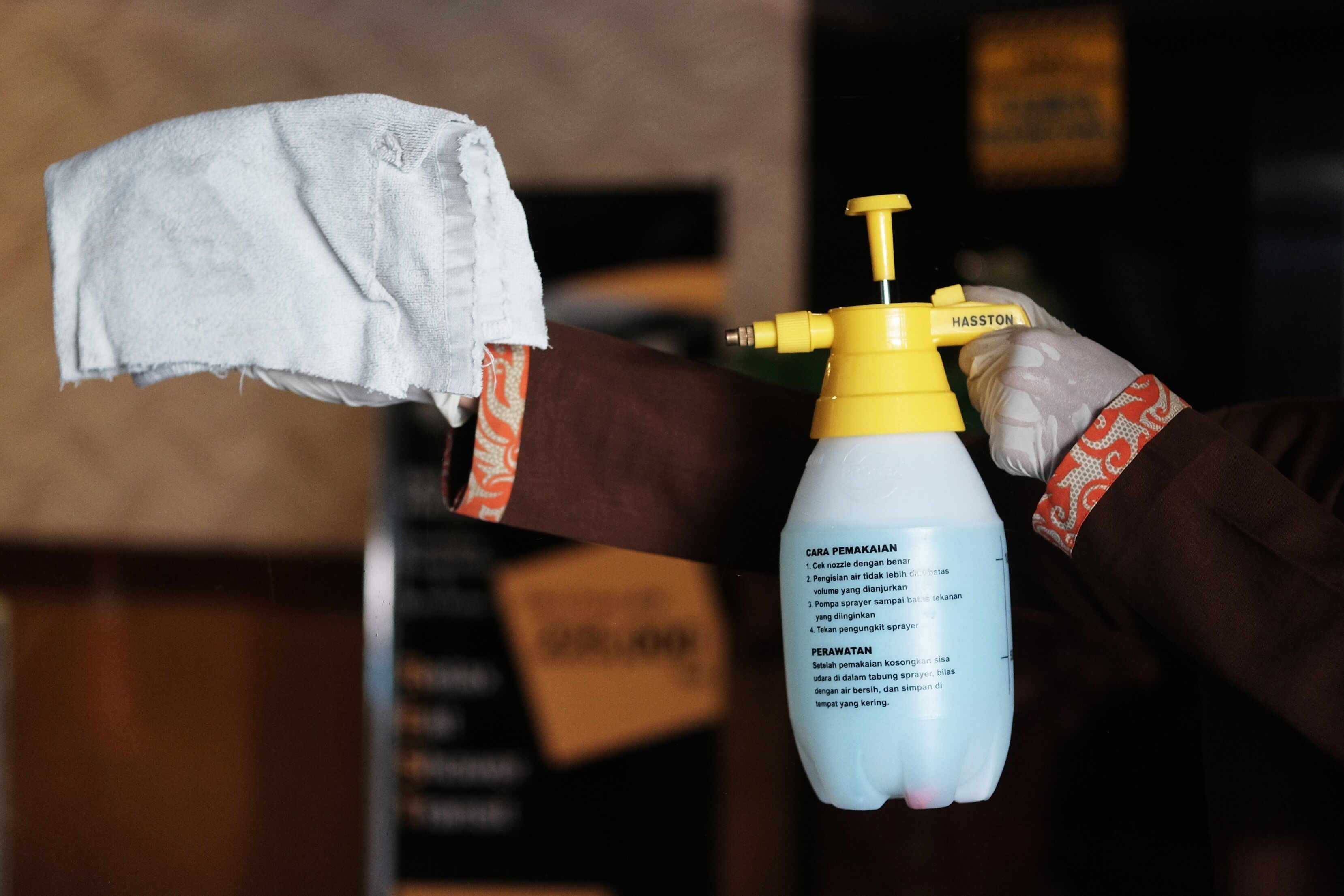 A person holding a spray bottle with a label and a cloth.