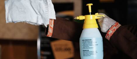 A person holding a spray bottle with a label and a cloth.