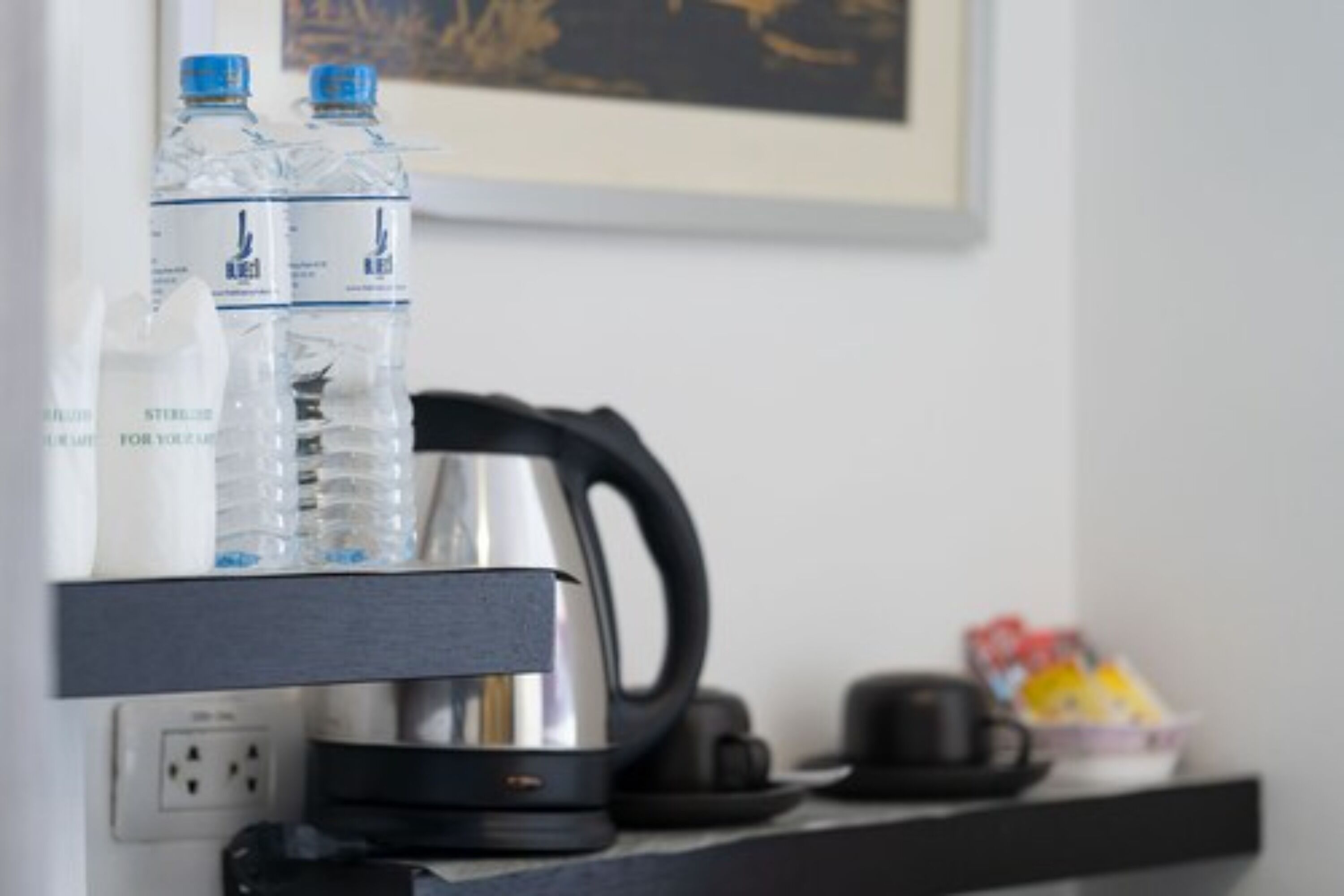 A kitchen counter with a kettle, a coffee maker, and two water bottles.