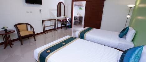 A hotel room with two beds, a desk, a chair, a TV, and a bathroom visible through an open door.