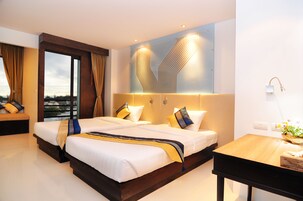 Una habitación de hotel moderna con dos camas, una mesa de madera y vistas a la ciudad.