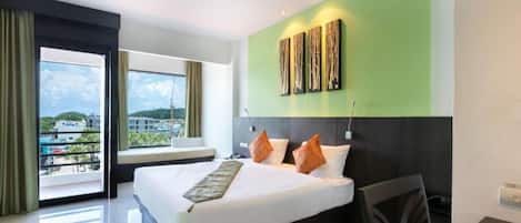 A hotel room with a large bed, a view of the city, and a green accent wall.