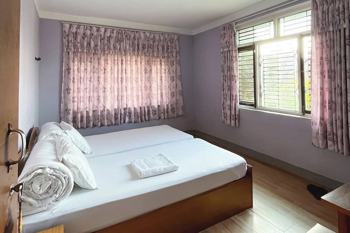 A hotel room with a bed, a desk, and a window with curtains.