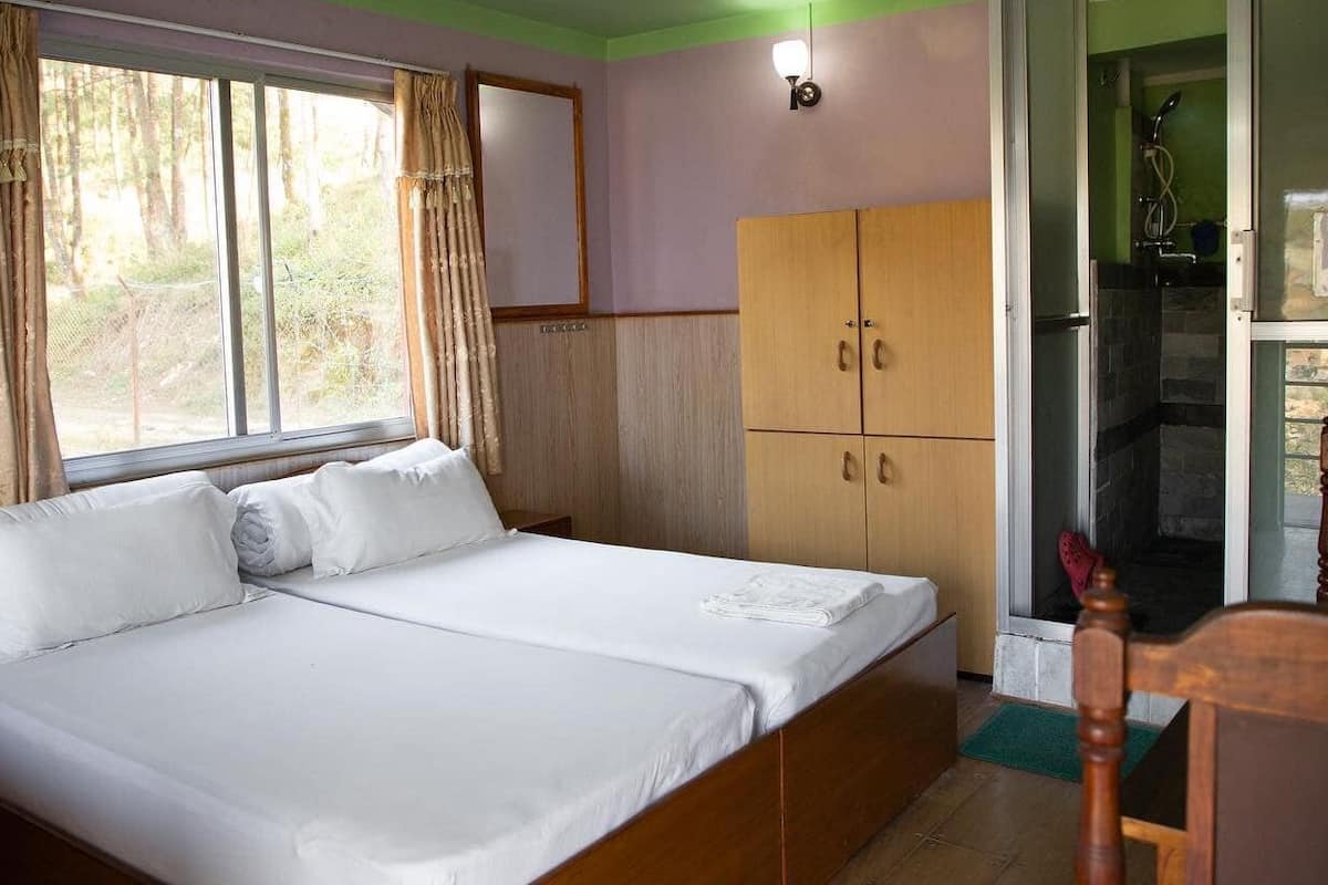 A room with a bed, wooden wardrobe, and a shower area.