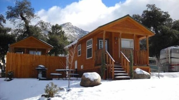 A wooden cabin with a porch, a staircase, and a snow-covered ground. - Oakzanita Springs RV Campground (Descanso)