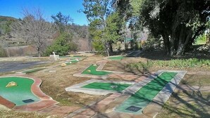 A miniature golf course with multiple holes, surrounded by trees and a clear sky. - Oakzanita Springs RV Campground (Descanso)