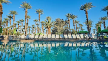 Una piscina al aire libre, sillones reclinables de piscina