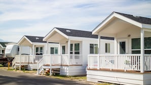 A row of white mobile homes with attached porches and a caravan parked in front. - Palm Springs RV Resort (Palm Desert)