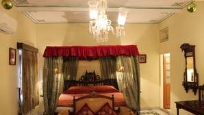 A bedroom with a large bed, ornate headboard, and a chandelier. - Madhuban - A Heritage Home (Jaipur)