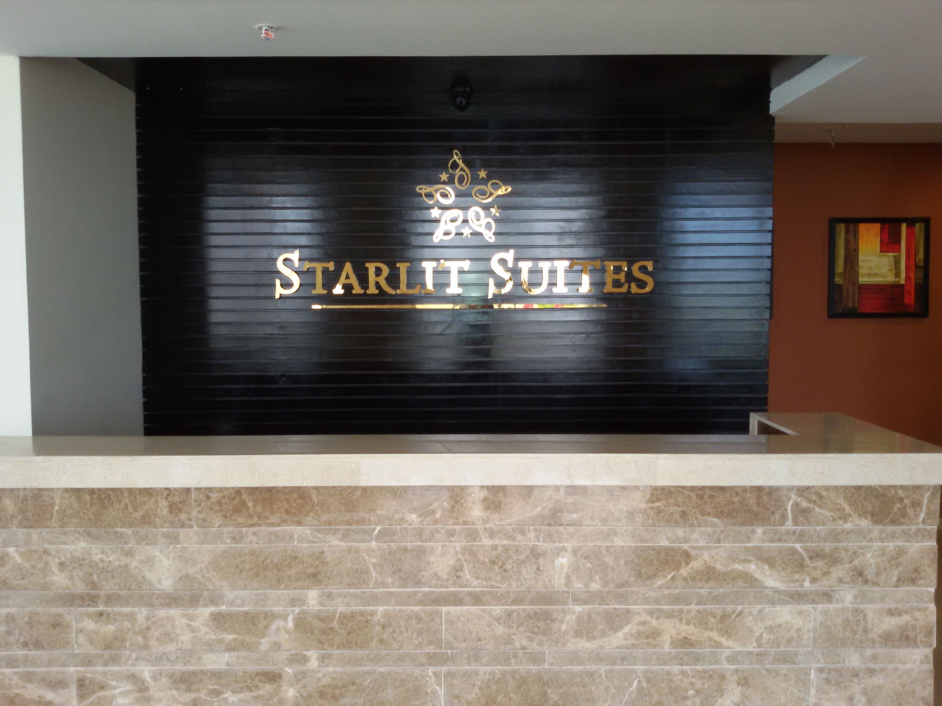 En receptionsdisk med en svart bakgrund där namnet ”Starlit Suites” visas i guldfärg.