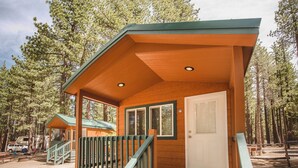 A wooden cabin with a porch, a door, and a staircase.