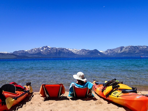 Kayaks on a sandy beach with mountains in the background.