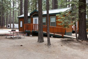 A cabin with a wooden deck, a picnic table, and a small porch.