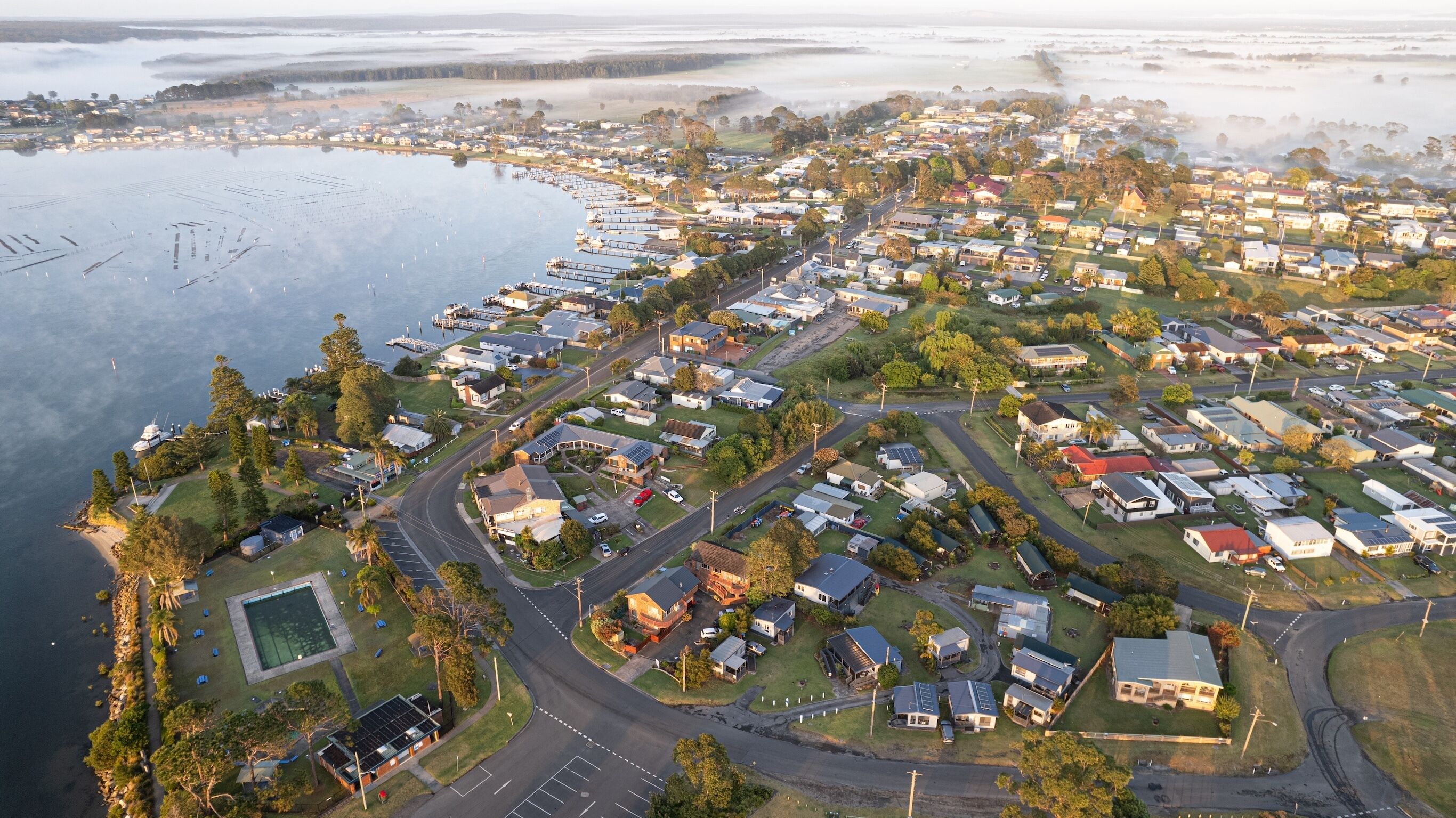 Vue aérienne d’un quartier résidentiel avec des maisons, des routes et un port de plaisance.