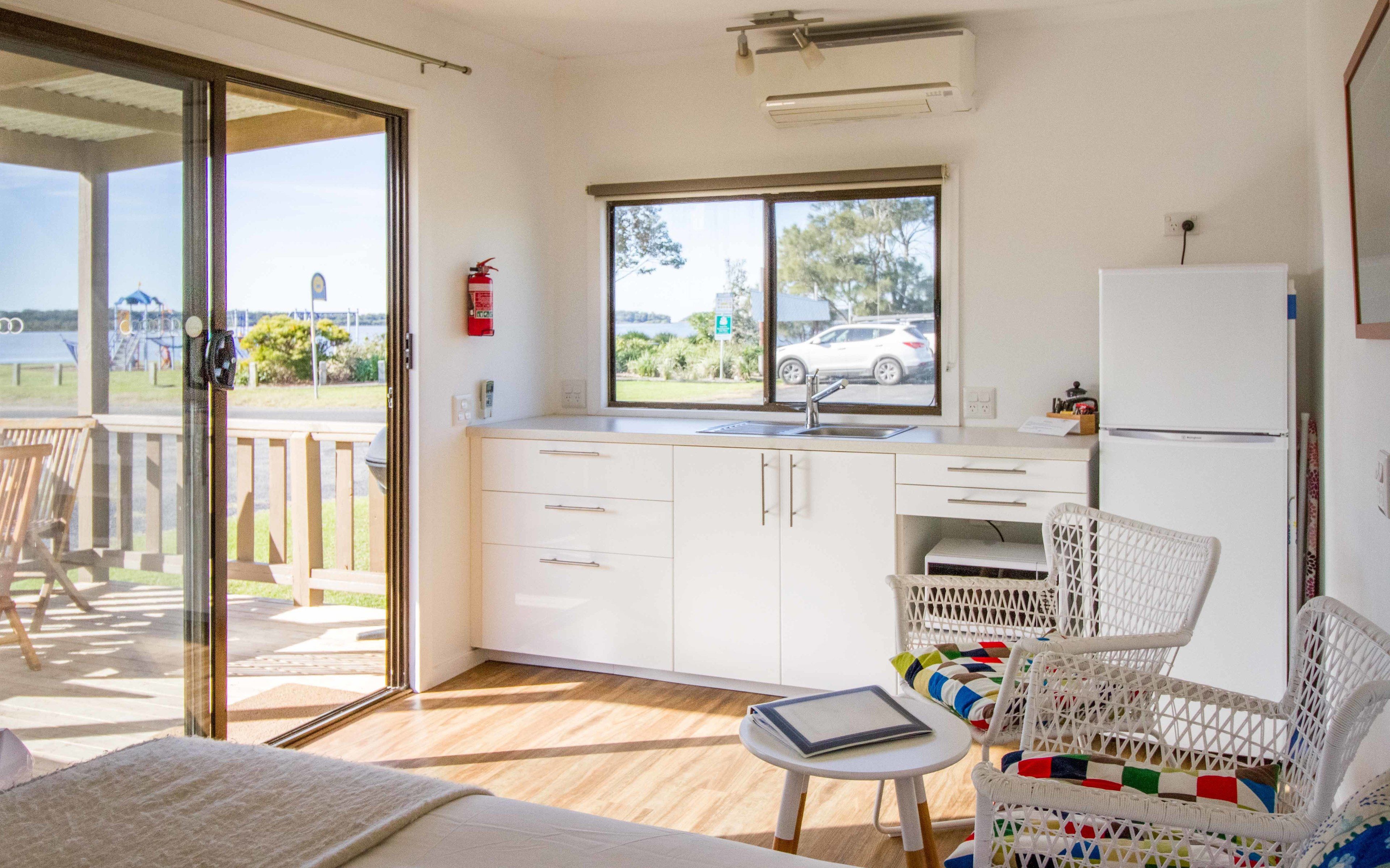 A compact kitchen with a window, a refrigerator, and a small dining area with a chair and table.