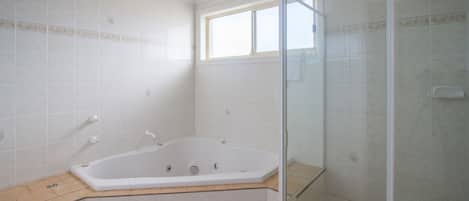 A bathroom with a freestanding bathtub, a glass shower enclosure, and a window providing natural light.