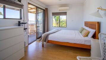 A bedroom with a bed, a chair, a window, and a door leading to an outdoor area.