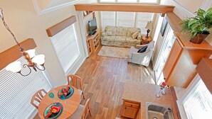 A compact kitchen with a dining area, a sofa, and a potted plant.