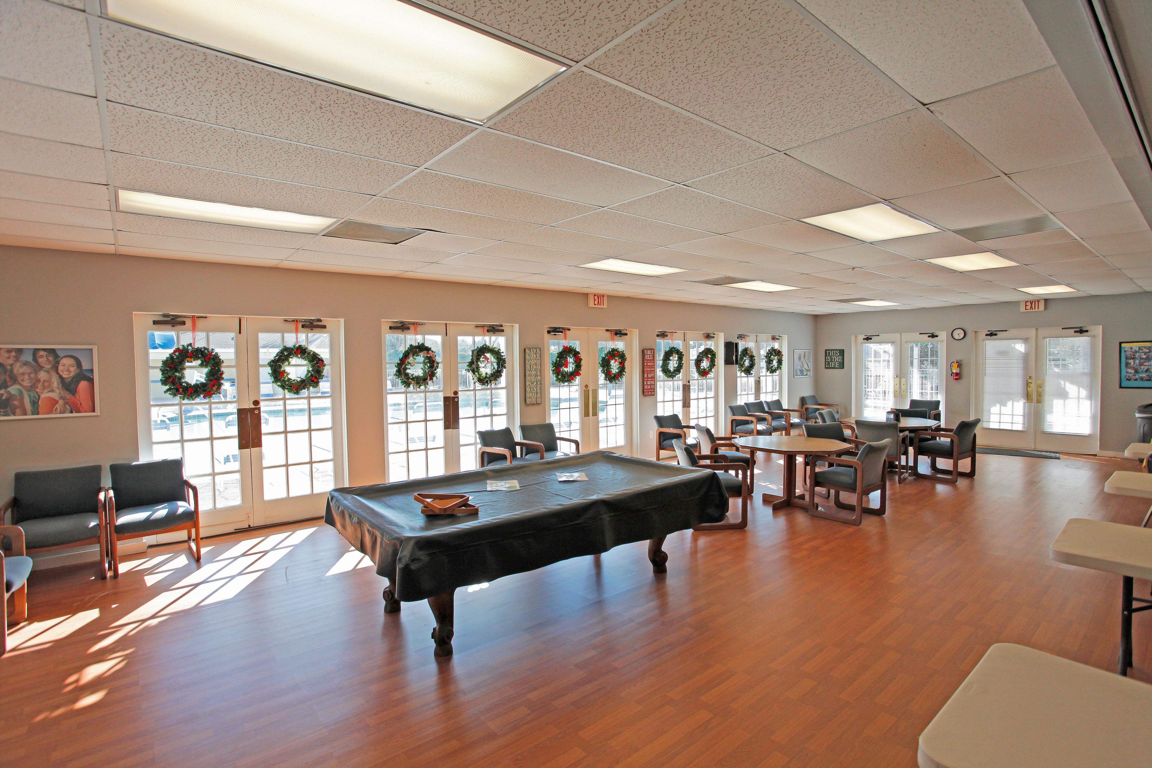 A spacious room with a pool table, multiple chairs, and a large window with a view.