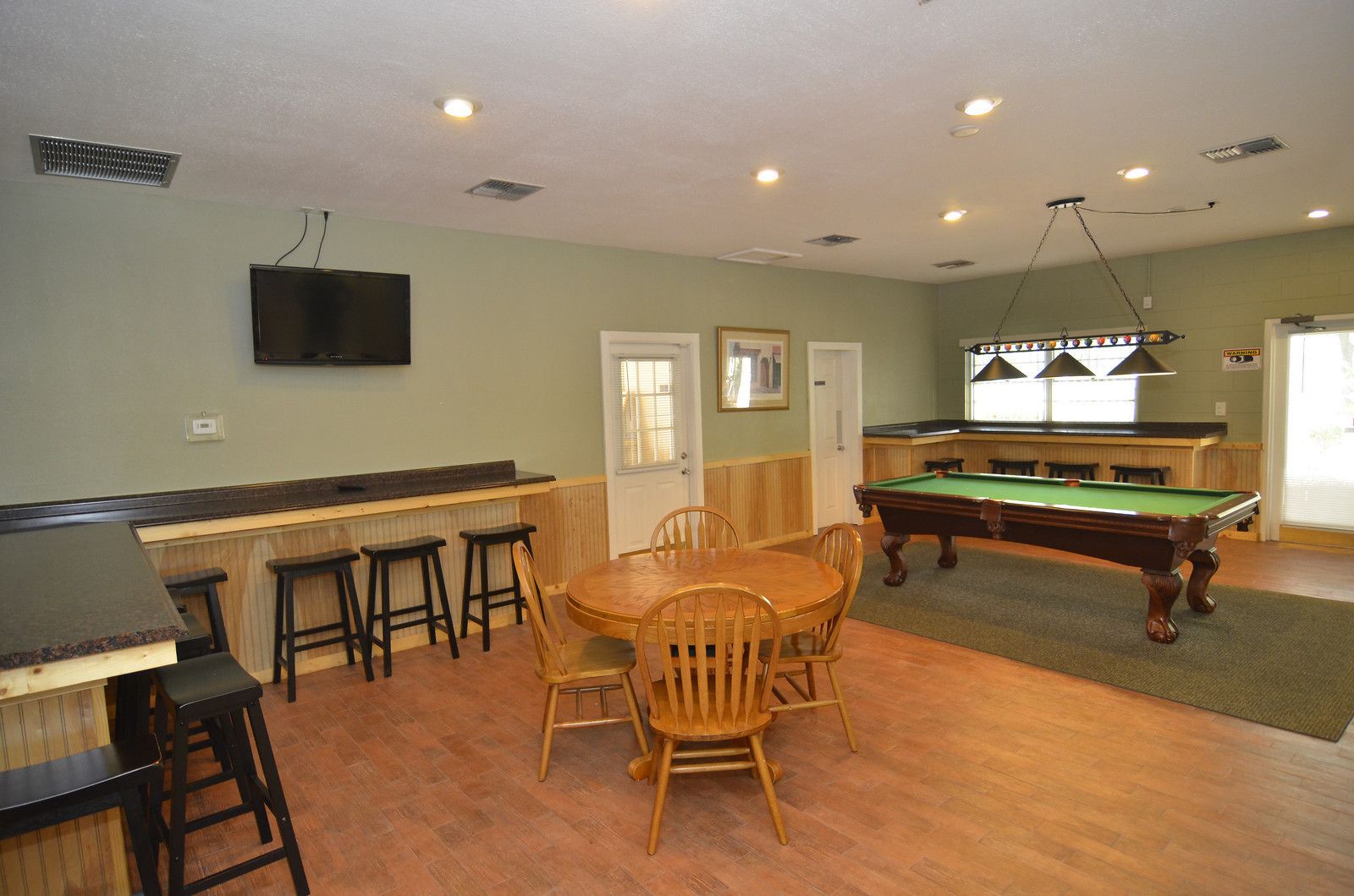 A pool table, bar area, and seating with a television above the bar.
