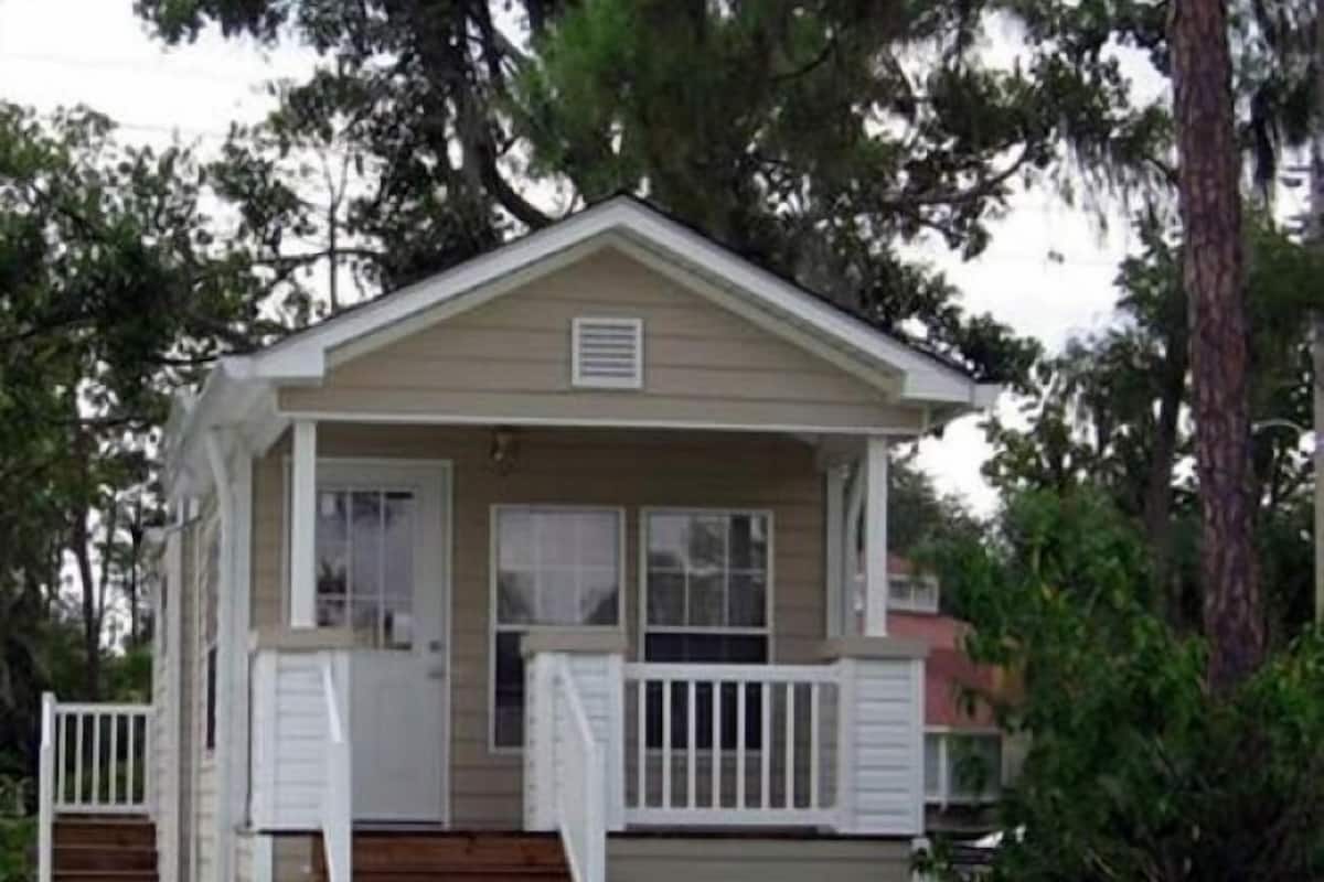 A small, single-story cabin with a front porch and a small deck.