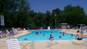 Une piscine avec plusieurs couloirs de nage, entourée de chaises longues et de parasols.