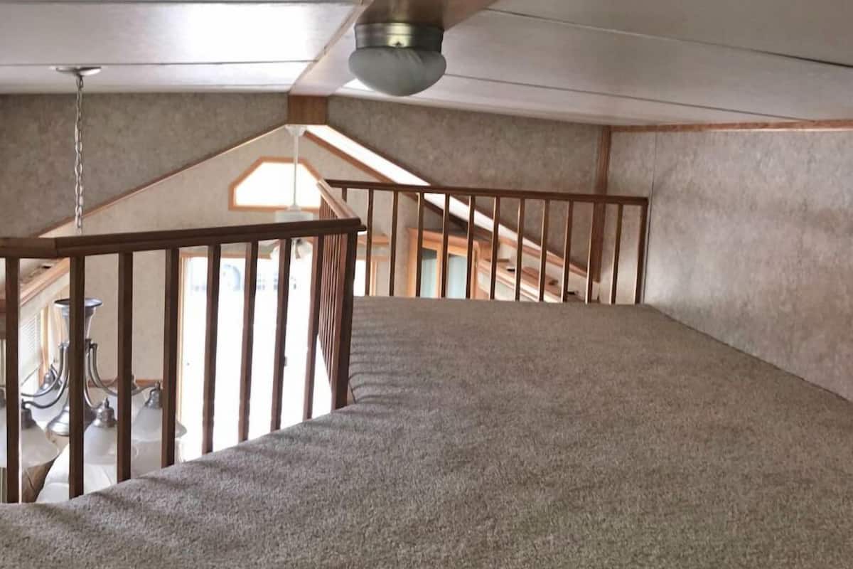 A high-ceilinged attic room with a sloped ceiling, a wooden staircase, and a skylight.