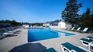 A rectangular swimming pool with lounge chairs and a building in the background. - Narrows Too Camping Resort (Trenton)