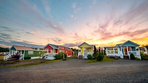 A row of colorful cabins with a gravel driveway and a scenic sunset in the background. - Narrows Too Camping Resort (Trenton)