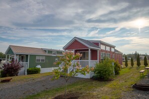 A row of mobile homes with a grassy yard and a small tree in the foreground.